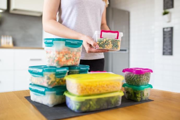 Femme occupée à préparer des Tupperware de légumes