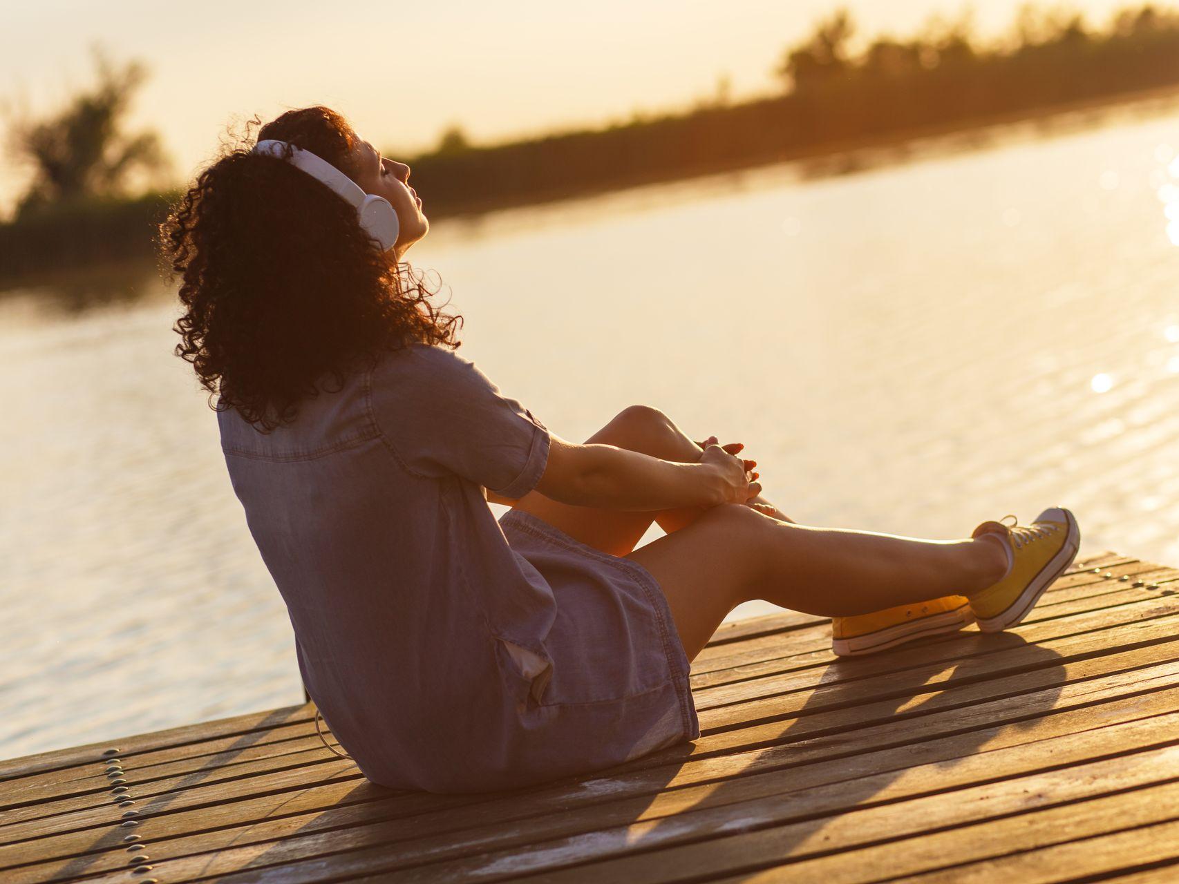 Femme qui écoute de la musique au soleil le long d'un fleuve