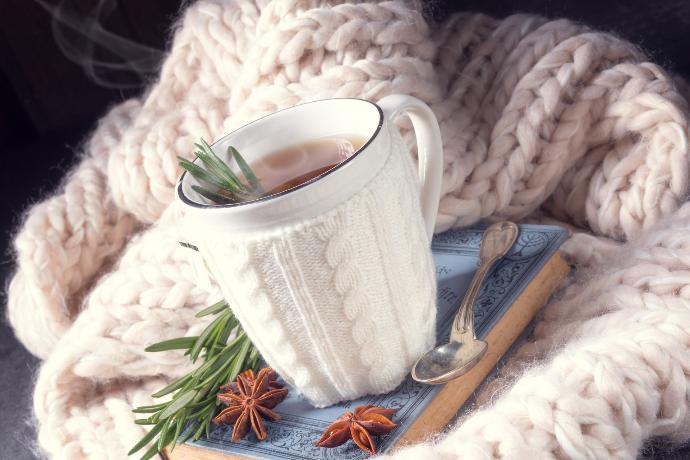 Tasse blanche avec du thé recouverte de laine avec de l'anis étoilé et du romarin