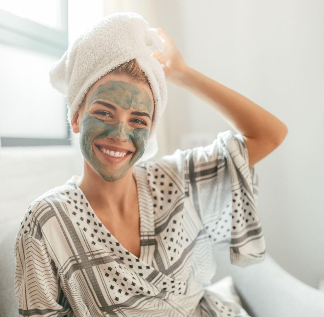 Jeune femme souriante avec un soin d'argile sur le visage 