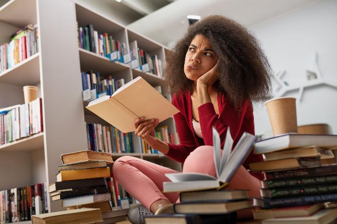 Jeune fille qui stress dans une bibliothèque un livre à la main